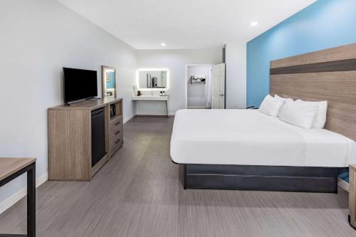 a hotel room with a bed and a flat screen tv at Baymont by Wyndham Freeport Texas in Freeport