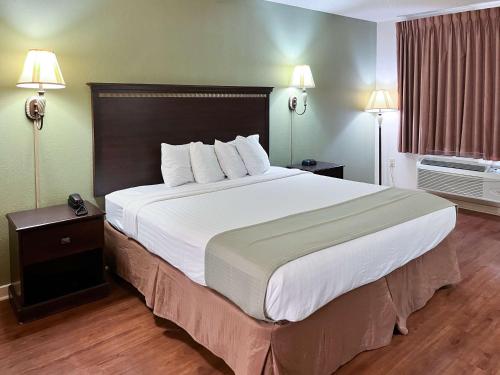 un grande letto in una stanza d'albergo con due lampade di Motel 6 Abbeville, AL ad Abbeville
