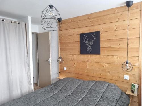 a bedroom with a wooden wall with a bed at Appartement très lumineux in Égat