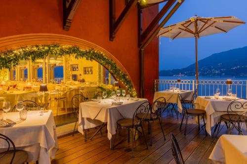 a restaurant with white tables and chairs and a large window at La Darsena Boutique Hotel & Restaurant in Tremezzo