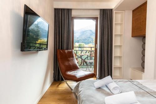 um quarto com uma cama, uma cadeira e uma janela em MOUNTAIN BASE Apartament Bellissimo em Zakopane