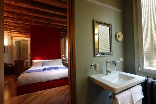 a bathroom with a bed and a sink and a mirror at Le Andrianelle in Malo