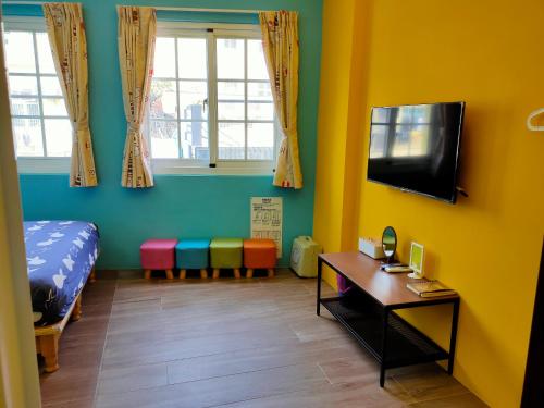 a room with a bed and a desk and a tv at ELLIE HOUSE in Xiaoliuqiu