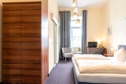 a bedroom with a bed and a large wooden closet at Hotel-Pension am Siegestor in Munich