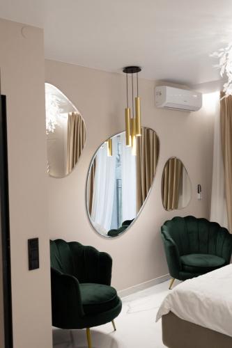 a bedroom with two green chairs and a mirror at Villa Grey Hotel in Duliby