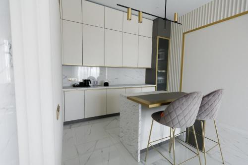 a kitchen with white cabinets and a table and chairs at Villa Grey Hotel in Duliby