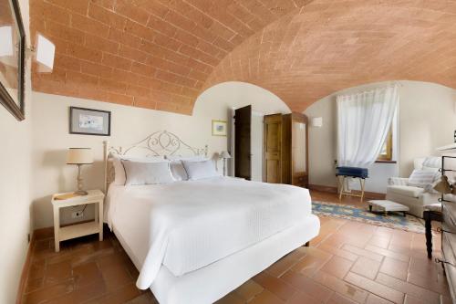 a bedroom with a large white bed and a chair at Villa Vignacce - Boutique Country Resort in Bettolle