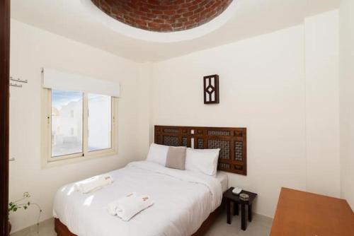 een slaapkamer met een groot wit bed en een raam bij Makadi Heights Elite Residence - Hurghada, Red Sea in Hurghada