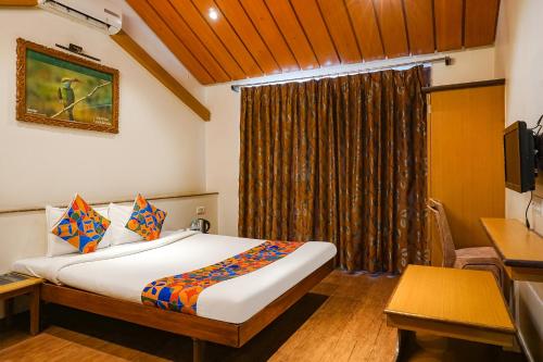 a bedroom with a bed and a desk and a television at FabHotel Lotus Resort in Aurangabad