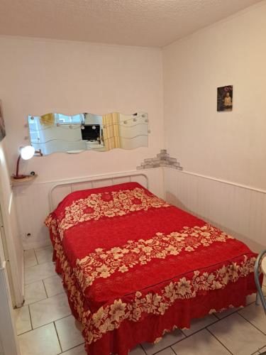 sypialnia z łóżkiem z czerwonym kocem w obiekcie Studio proche de Perpignan w mieście Peyrestortes