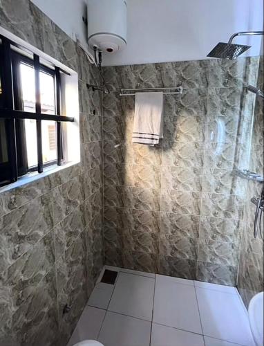 La salle de bains est pourvue d'une douche, de toilettes et d'une fenêtre. dans l'établissement Cosy Emerge, à Lomé