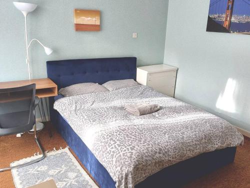 a bedroom with a bed with a blue headboard and a desk at Bloomsbury 2 room flat in London