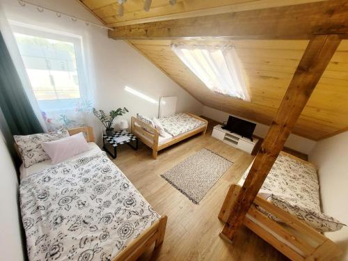 une chambre mansardée avec deux lits et une chambre avec dans l'établissement Apartamenty i pokoje gościnne pod lasem, à Nadarzyn