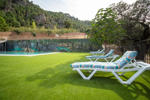 two lounge chairs sitting on a green lawn at Apartamentos 7 puentes sierra Cazorla Casa Encina in Burunchel