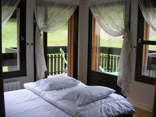 Schlafzimmer mit einem Bett und einem Fenster mit Vorhängen in der Unterkunft Le Fayard in Arâches-la-Frasse