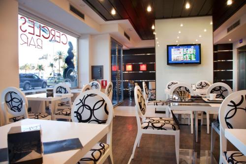 a restaurant with white tables and chairs and a tv at Hotel Boutique Estrella del Mar in Peñíscola