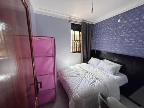a small bedroom with a bed and a purple wall at Safari Lake view apartments, Muyenga in Kampala