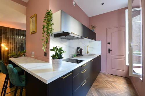 une cuisine avec des murs roses et un comptoir blanc dans l'établissement Suite jacuzzi, chic romantique climatisé à 50 m du metro, à Villeurbanne
