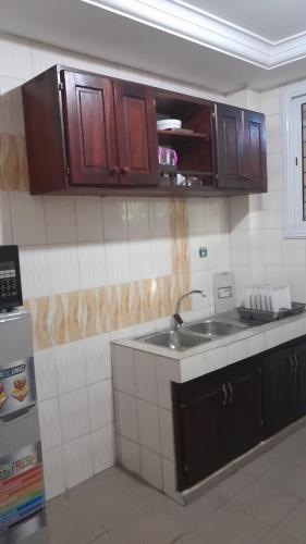 - une cuisine avec des placards en bois et un évier dans l'établissement OLD Bonapriso Paisible Appart meublé 2 Chambres, à Douala