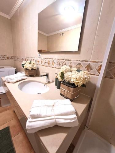 a bathroom with a sink and a mirror and flowers at El Sultán 71 Corralejo in Corralejo