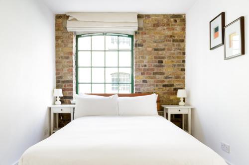 a bedroom with a white bed and a brick wall at Designer Warehouse Two Bedrooms Converted, London Bridge in London