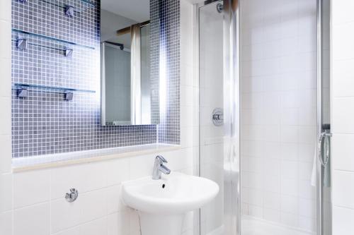 a white bathroom with a sink and a shower at Designer Warehouse Two Bedrooms Converted, London Bridge in London