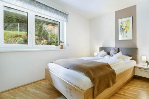biała sypialnia z dużym łóżkiem i 2 oknami w obiekcie Apartment mit Garten Alpinum Residence Lungau TOP 08 w mieście Tamsweg