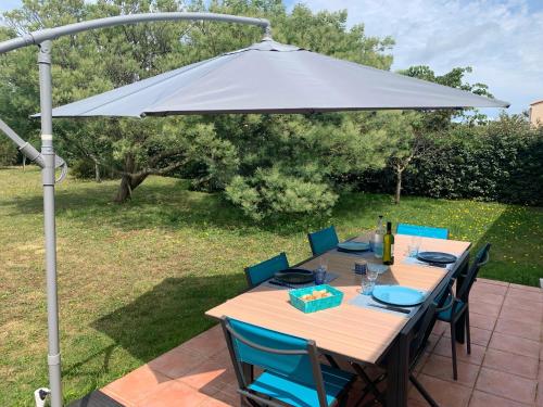 una mesa con sombrilla en el patio en Maison Familiale Proche Plage, Marché & Commerces - 6 pers. Classée 3 étoiles, en La Brée-les-Bains