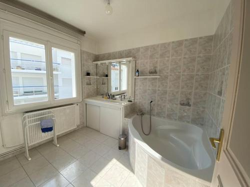 a white bathroom with a tub and a sink and a tub at Maison entre marché et plages de Royan in Royan