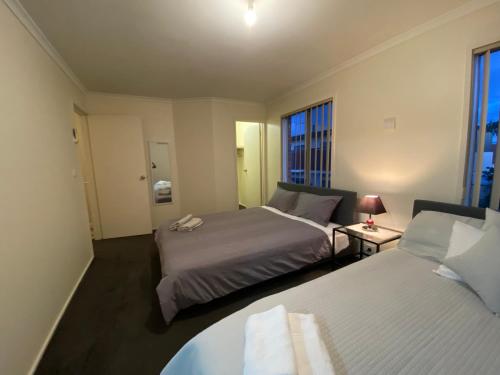 una camera da letto con due letti e un tavolo con una lampada di 5 Beds-Whole House-Carrum Beach- Patterson Lake-Fully Furnished a Carrum