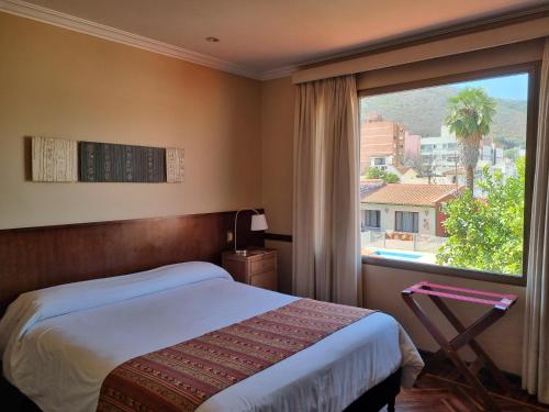 a bedroom with a bed and a large window at Hotel Boutique La Candela in Salta