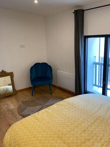 - une chambre avec une chaise bleue à côté d'une fenêtre dans l'établissement Maison Marceau Gruissan, à Gruissan