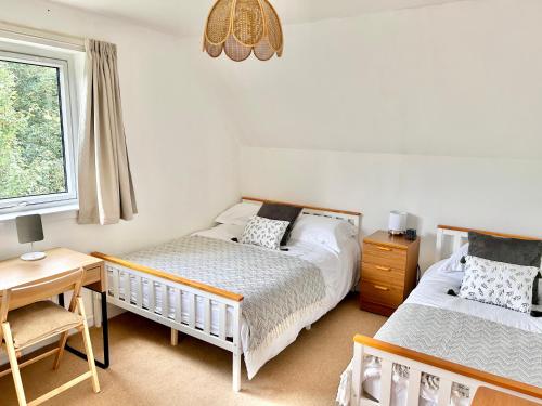 a bedroom with two beds and a desk and a window at Homestead House, Fort Augustus in Fort Augustus