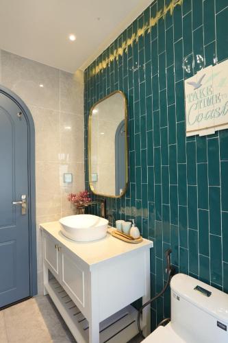 a green tiled bathroom with a sink and a mirror at KB Villas 58 in Bình Sum