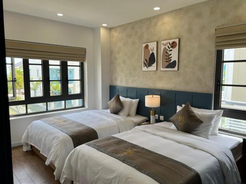 1 dormitorio con 2 camas y 2 ventanas en KB Villas en Bình Sum