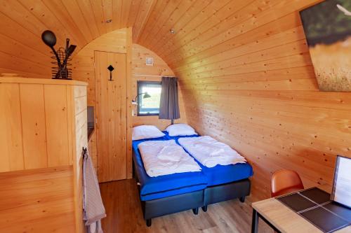 1 dormitorio con 2 camas en una habitación con paredes de madera en Woodlodge High Chaparral en Oirsbeek