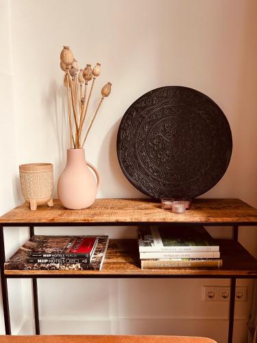 a shelf with a black plate and a vase and books at Monumentale stadswoning in hartje binnenstad in Maastricht