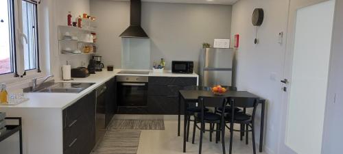 a kitchen with black cabinets and a table with stools at Cabanelas Country House - Casa do Luís in Vale de Cambra