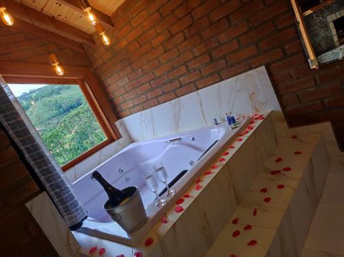 a bathroom with a tub with a bottle of wine in it at Pousada das Castanheiras in Monte Verde