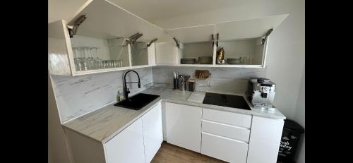 a white kitchen with white cabinets and a sink at Appartement vue mer , plage à 50m in Six-Fours-les-Plages