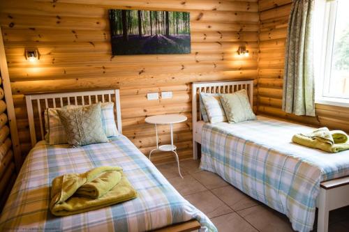 two beds in a log cabin bedroom with a table at Quail Lodge - Nordic Log Cabin in Selby