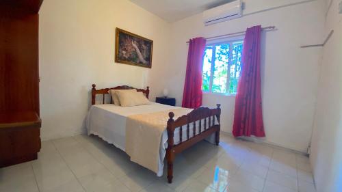 a bedroom with a bed and a window with red curtains at 2 Bedroom Apartment 250 meters from the Beach in Poste Lafayette
