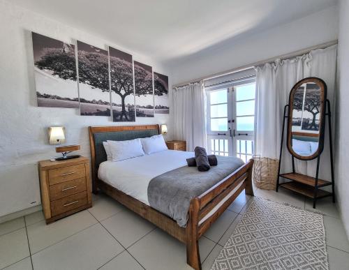 a bedroom with a large bed and a mirror at Oceanfront Greek Style Gem in Ballito