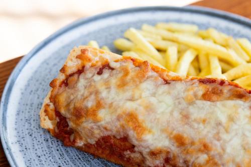 a blue plate with a piece of cheese pizza and french fries at The Valley Hotel, Anglesey in Valley