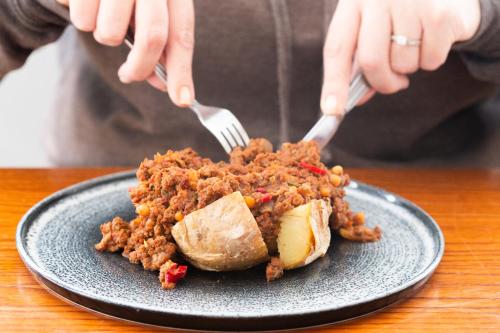 a person eating food on a plate with fork and knife at The Valley Hotel, Anglesey in Valley
