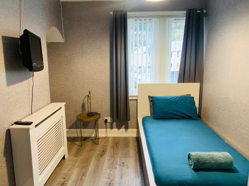 1 dormitorio con cama con sábanas azules y ventana en Nevis Rooms - Self check in with free onsite Parking, en Inverlochy