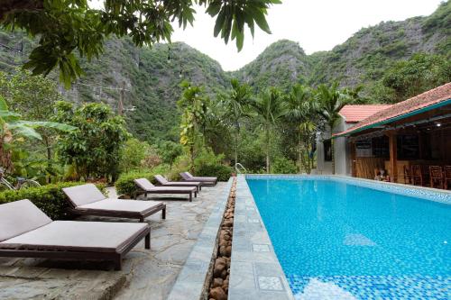 una piscina en un complejo con montañas en el fondo en Tam Coc Luxury Homestay, en Ninh Binh