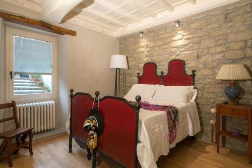 a bedroom with a red bed in a stone wall at Casa Sofia in Fiesole
