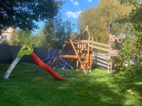 un parque infantil con un tobogán rojo y un parque infantil en Domki całoroczne - u Ptaka - Miłków, en Miłków