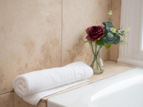 a bathroom with a vase of flowers and a towel at Pass the Keys Cozy Hidden Gem 2Br Near Station Shops in London